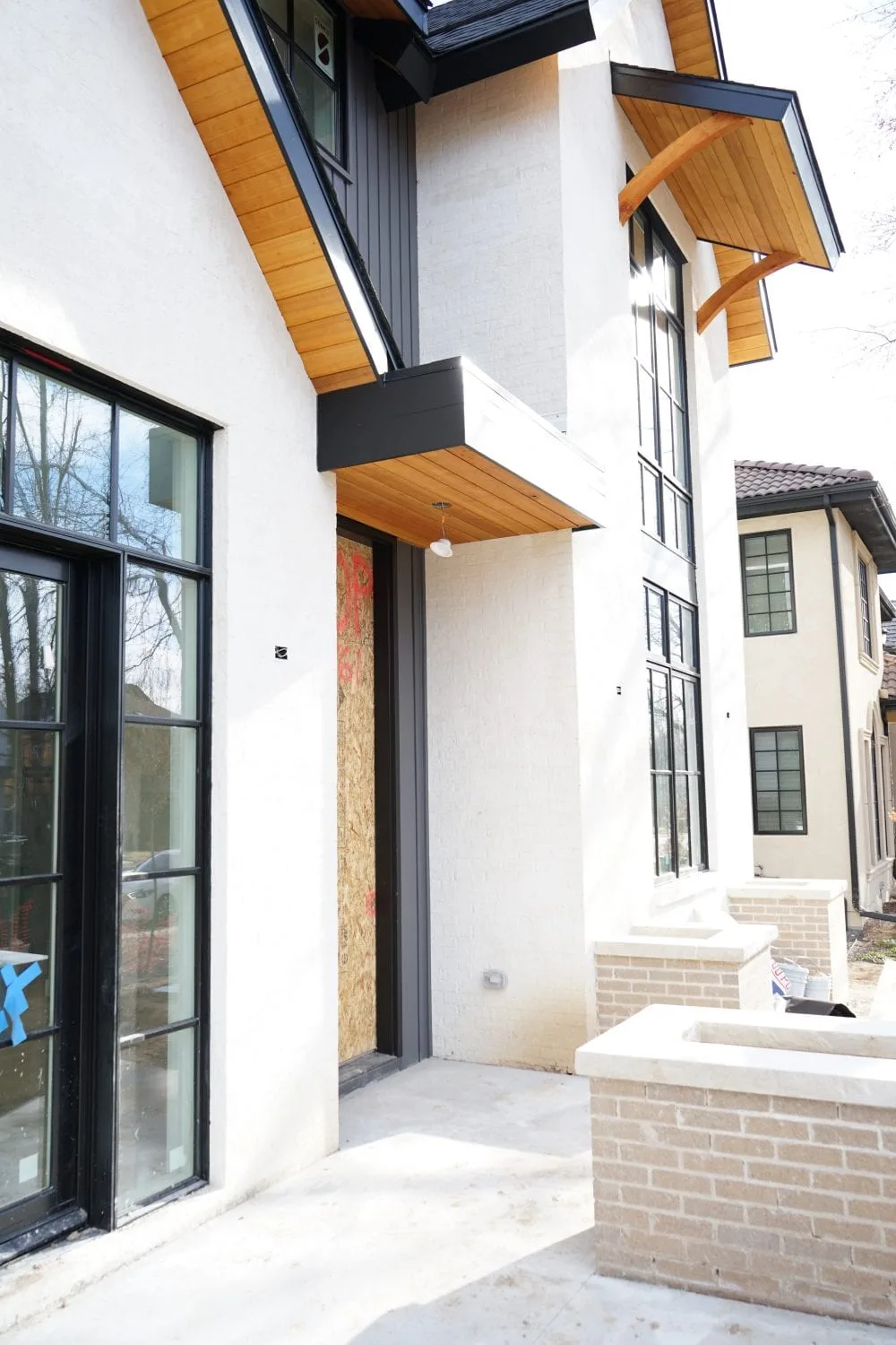 Modern house exterior with black-framed windows and a wood entry awning
