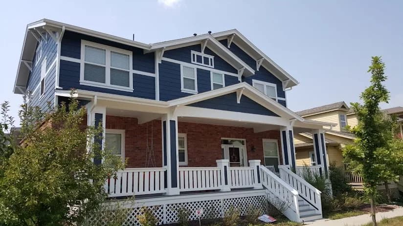 Two-story blue craftsman with white trim, brick accents and a covered front porch