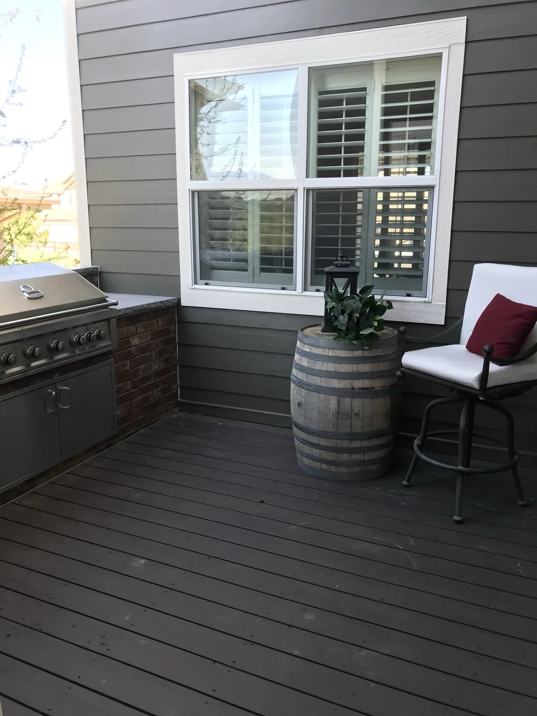 Close-up of freshly painted gray siding, brick and window trim on a covered deck