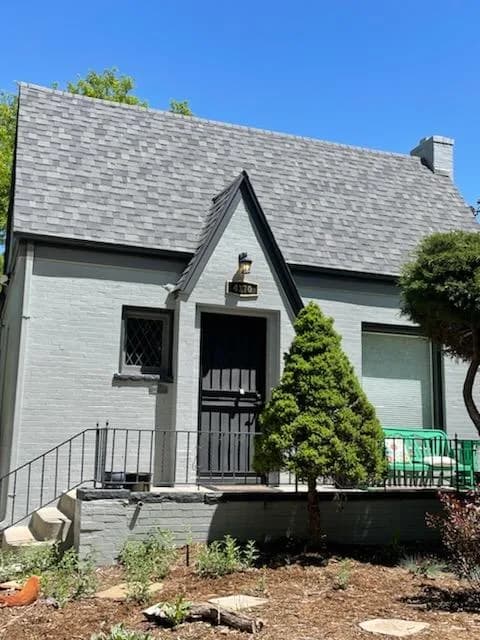 Tudor-style cottage with gray painted brick and a black door and trim