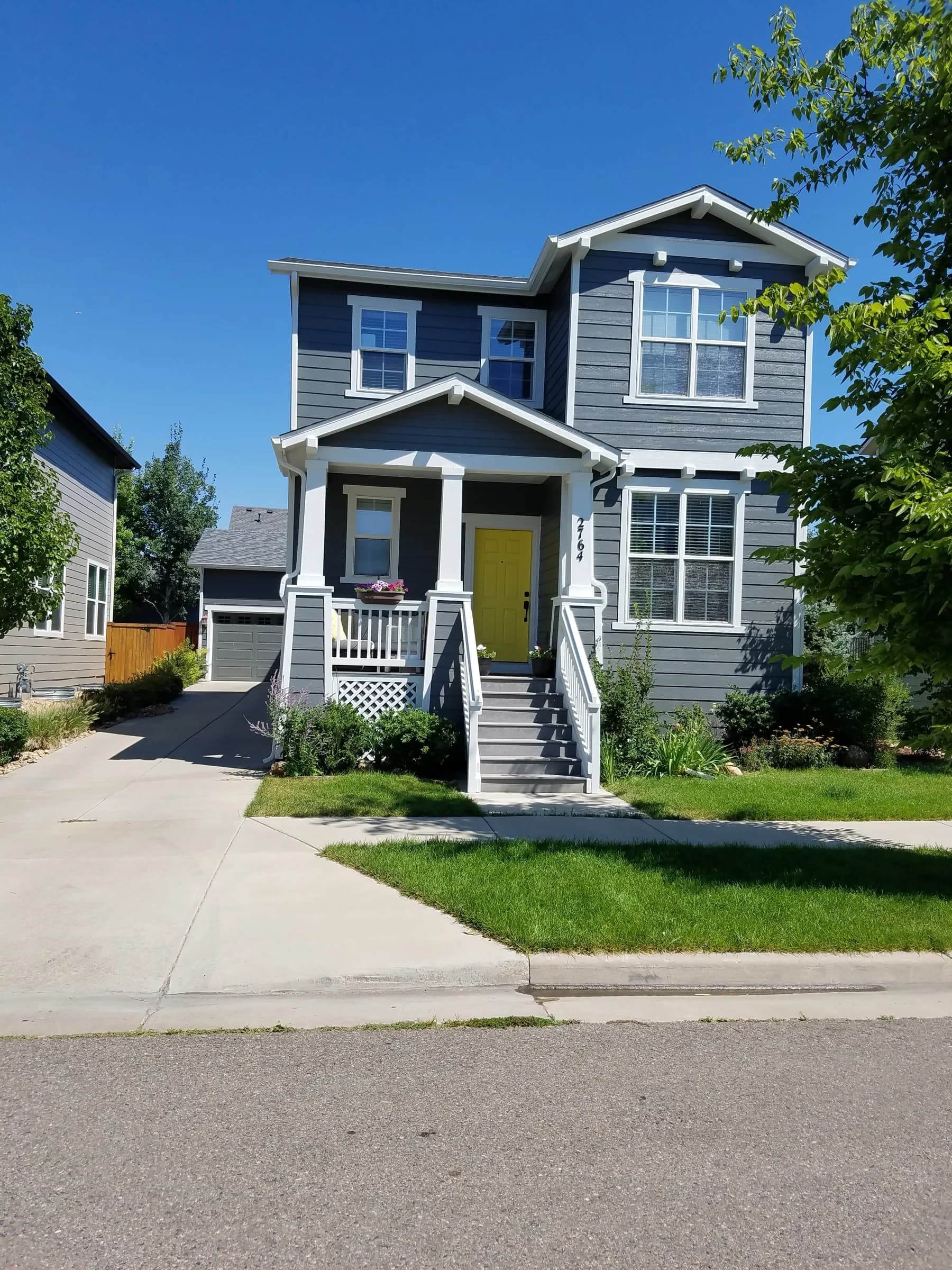 Gray craftsman house with white trim and a bold yellow front door