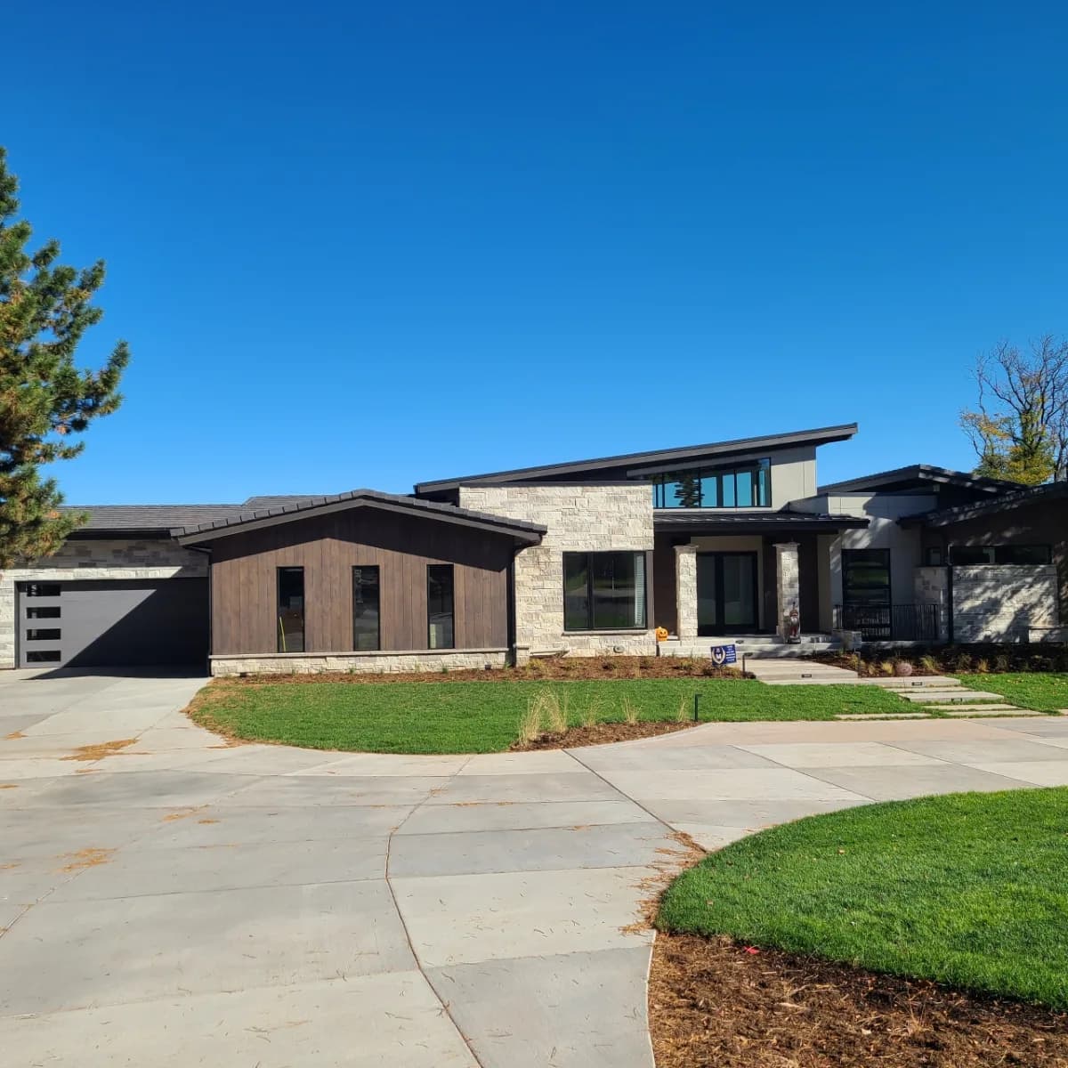 Modern mountain-contemporary home with dark wood and stone siding and a low-pitch roof