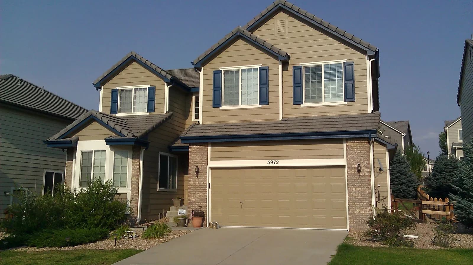 Tan two-story suburban house with dark blue shutters