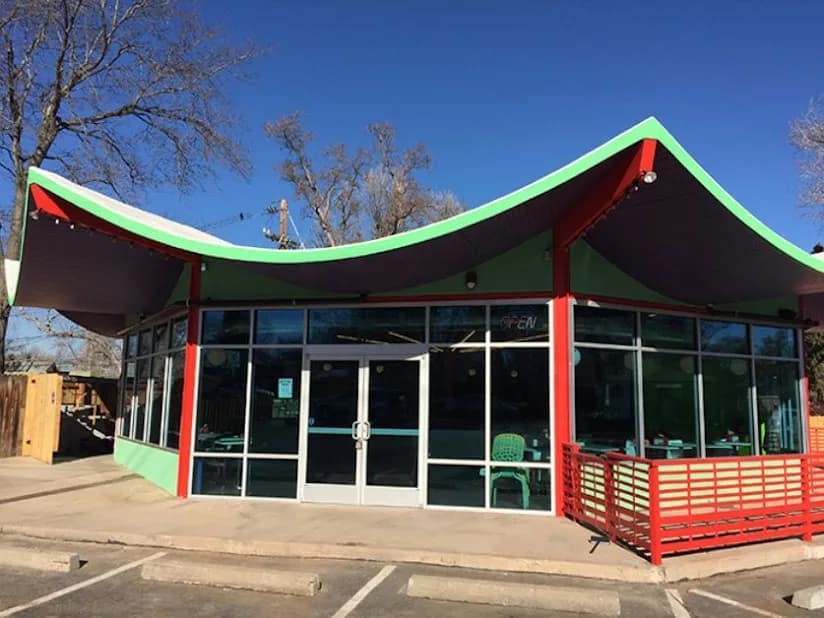 Commercial building with a bold red and green curved roofline and big storefront windows