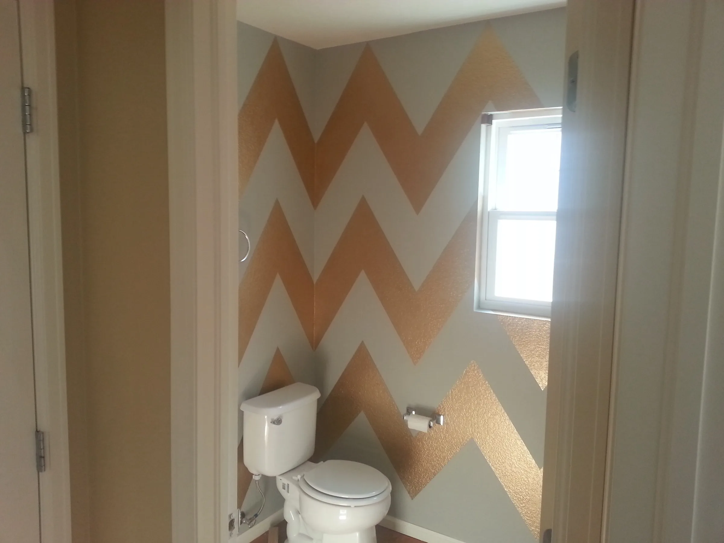 Gold and gray chevron accent wall in a powder bathroom