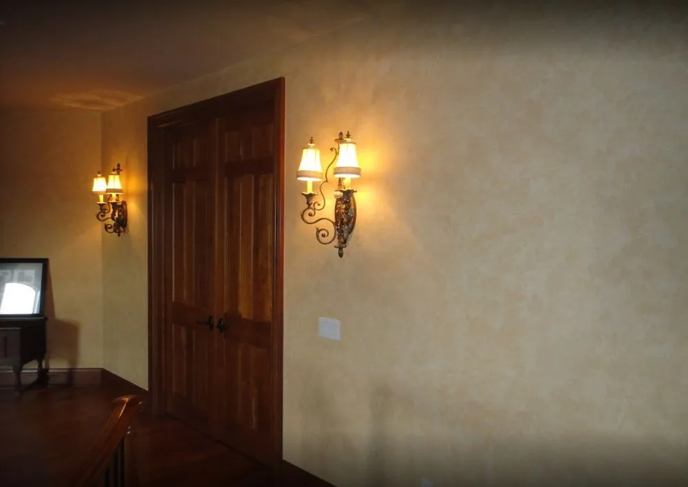 Dark bronze Venetian plaster finish on an entry wall with sconce lighting