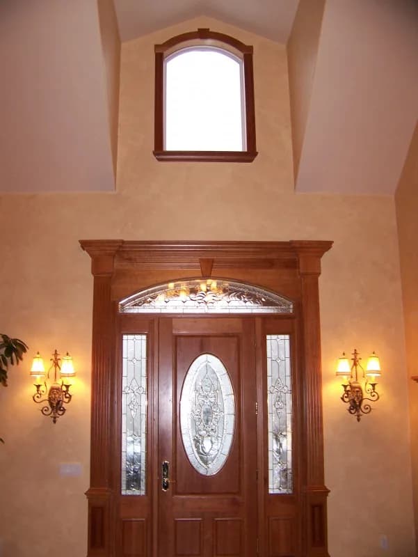 Two-story front entry with a painted door and wall sconces